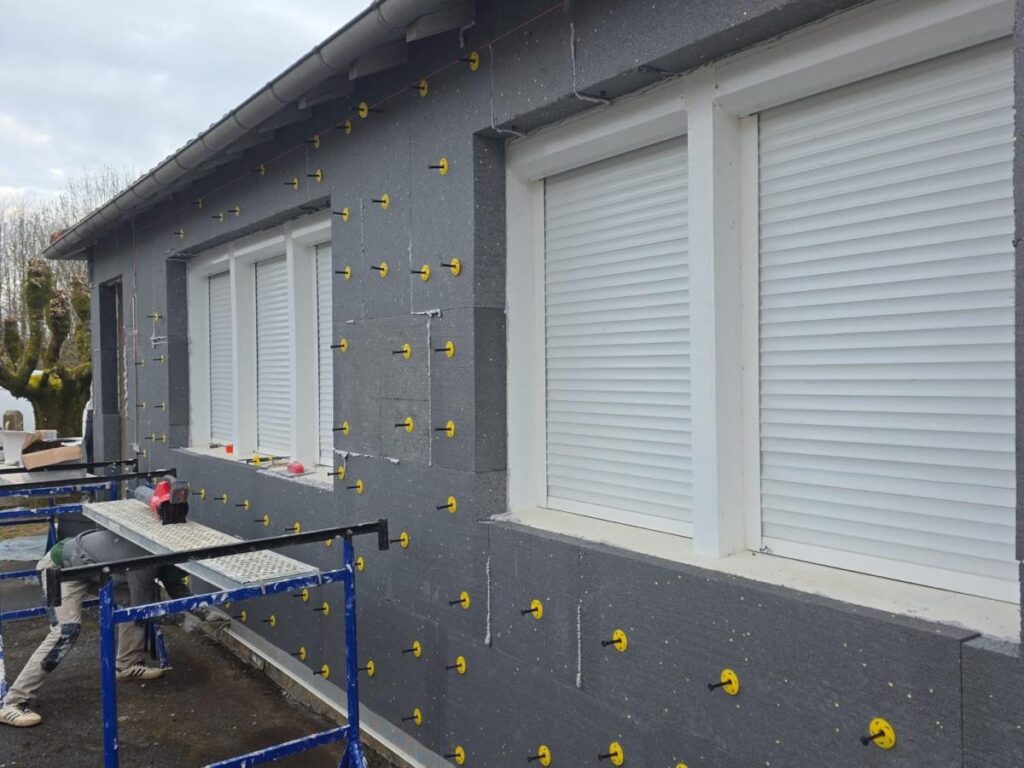 Isolation Thermique Extérieure : Pose de Panneaux ITE Installation d'isolation thermique par l'extérieur (ITE) avec panneaux de polystyrène gris et fixations jaunes.